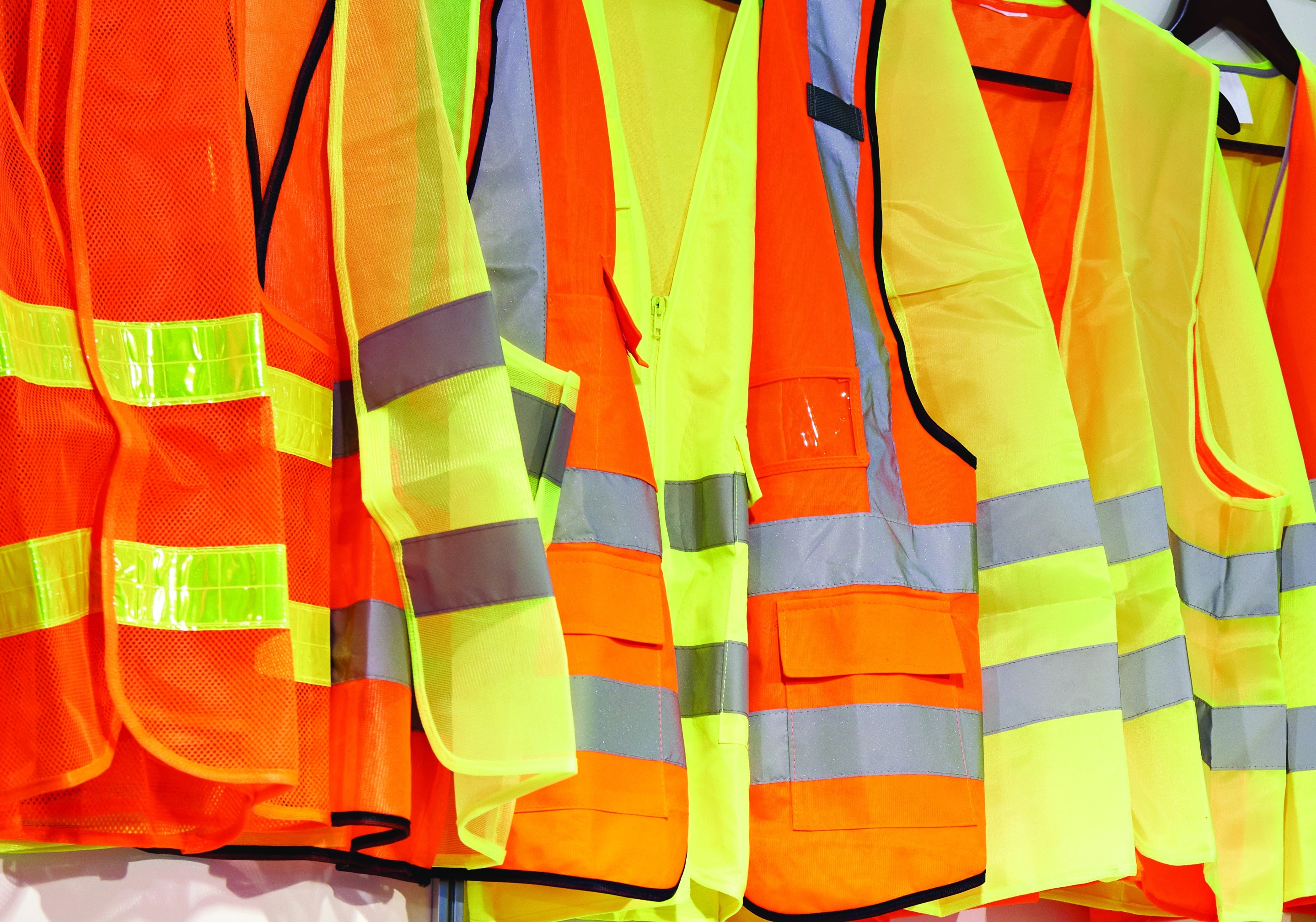 HazTek Careers - Array of orange and green safety jackets and triangle reflectors hanging on a wall.