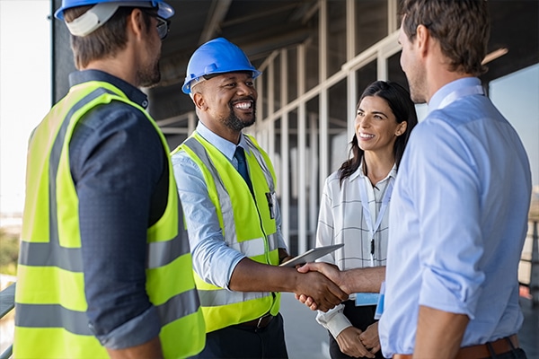 Safety consulting company professional shaking hands with a client, while two others watch and smil